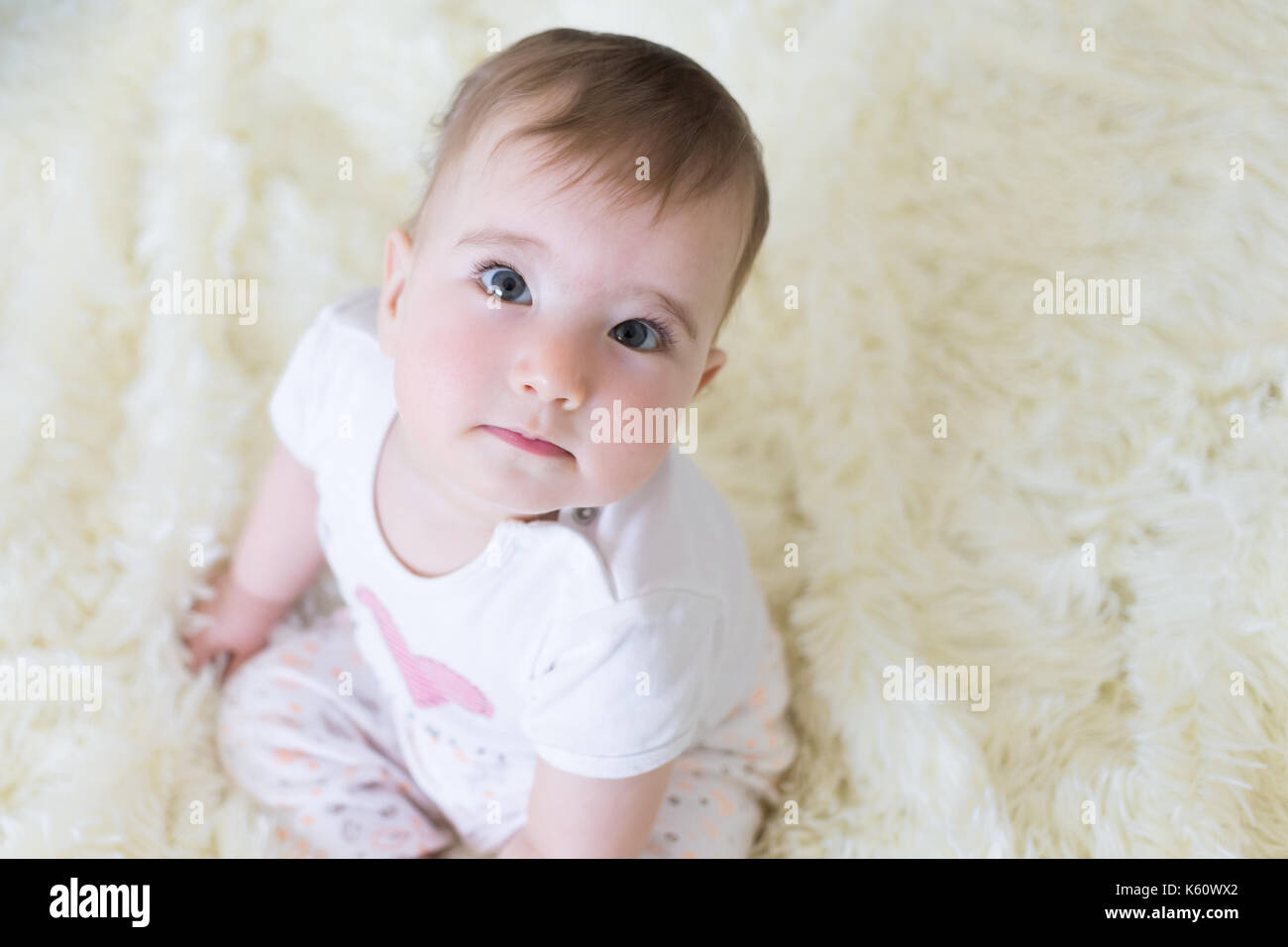 Small child looking up sitting on the bed closeup portrait. Stock Photo
