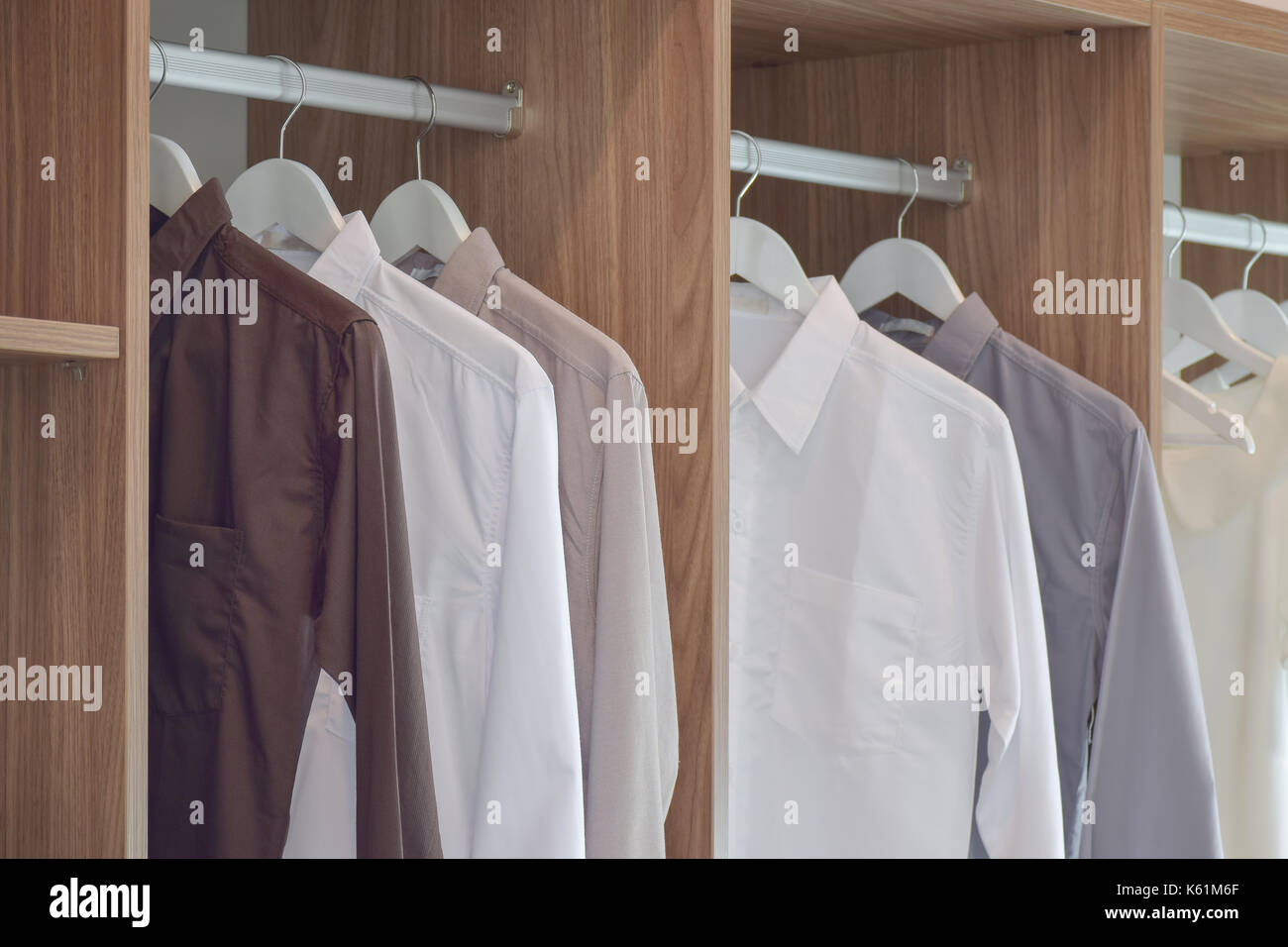 Classic color shirts hanging in wooden wardrobe Stock Photo