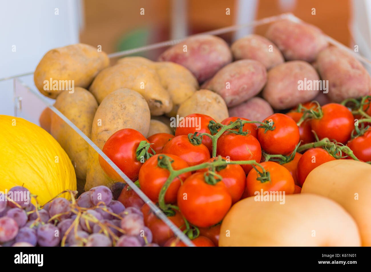 red tomatoes, yellow and red potatoes, black grapes, yellow melons in transparent boxes Stock Photo