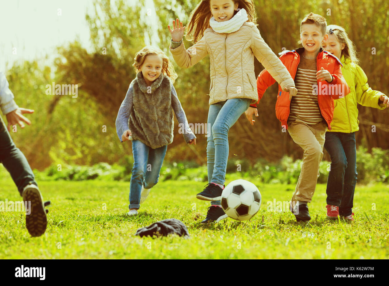 Happy smiling kids playing football outdoors in sunny day Stock Photo ...