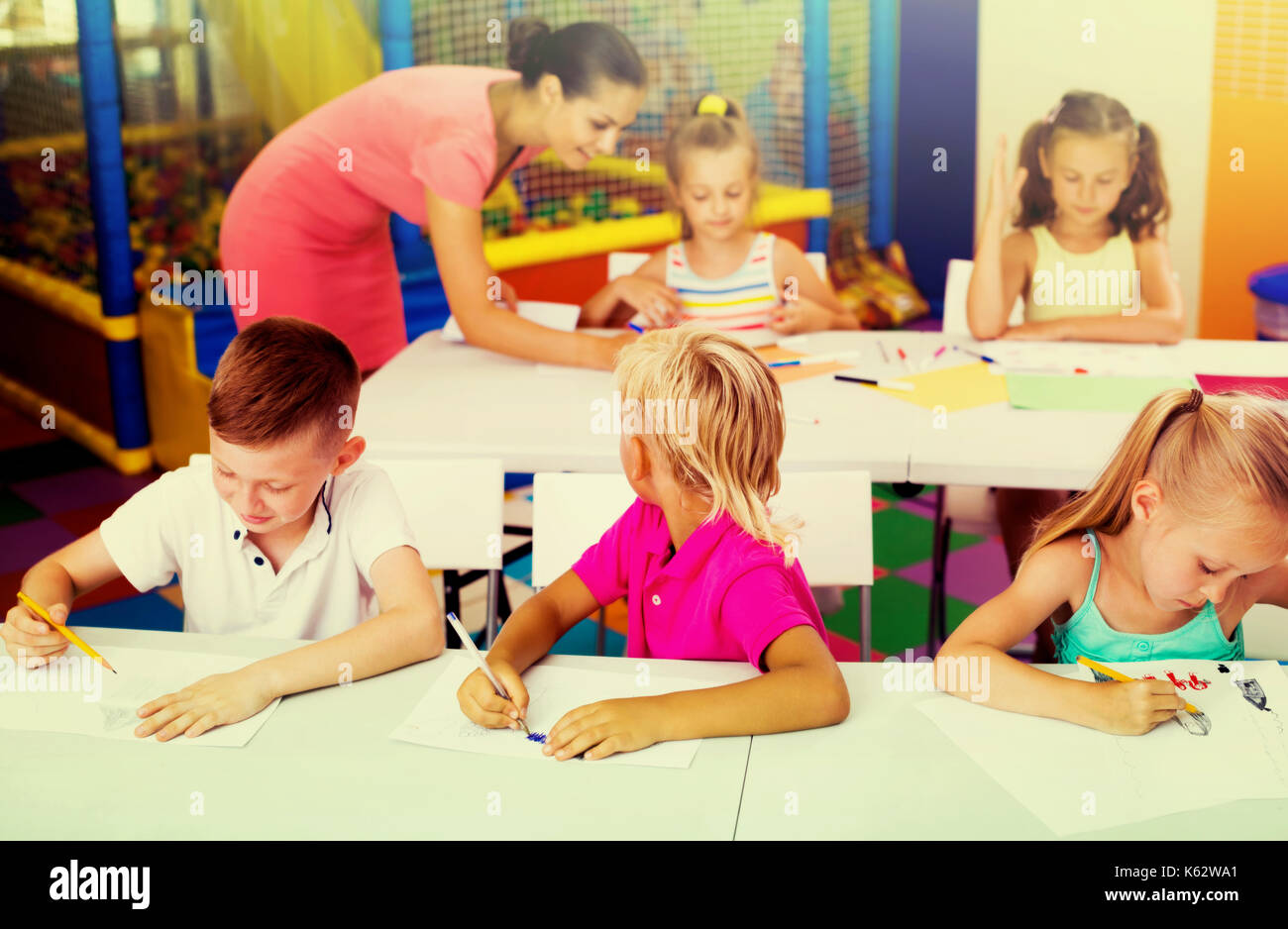 Primary School Kids Sitting At The Desks And Doing Exercises At
