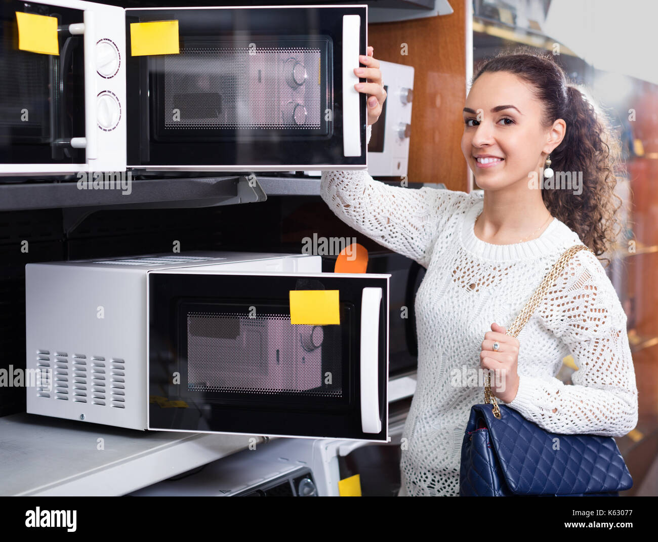Smiling brunette girl choosing new microwave in supermarket Stock Photo