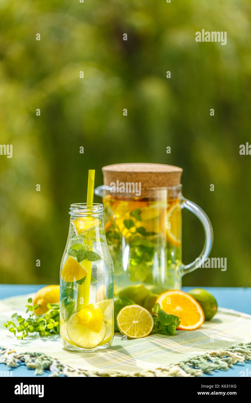 Lemonade pitcher with lemon, mint and ice on garden table Stock Photo