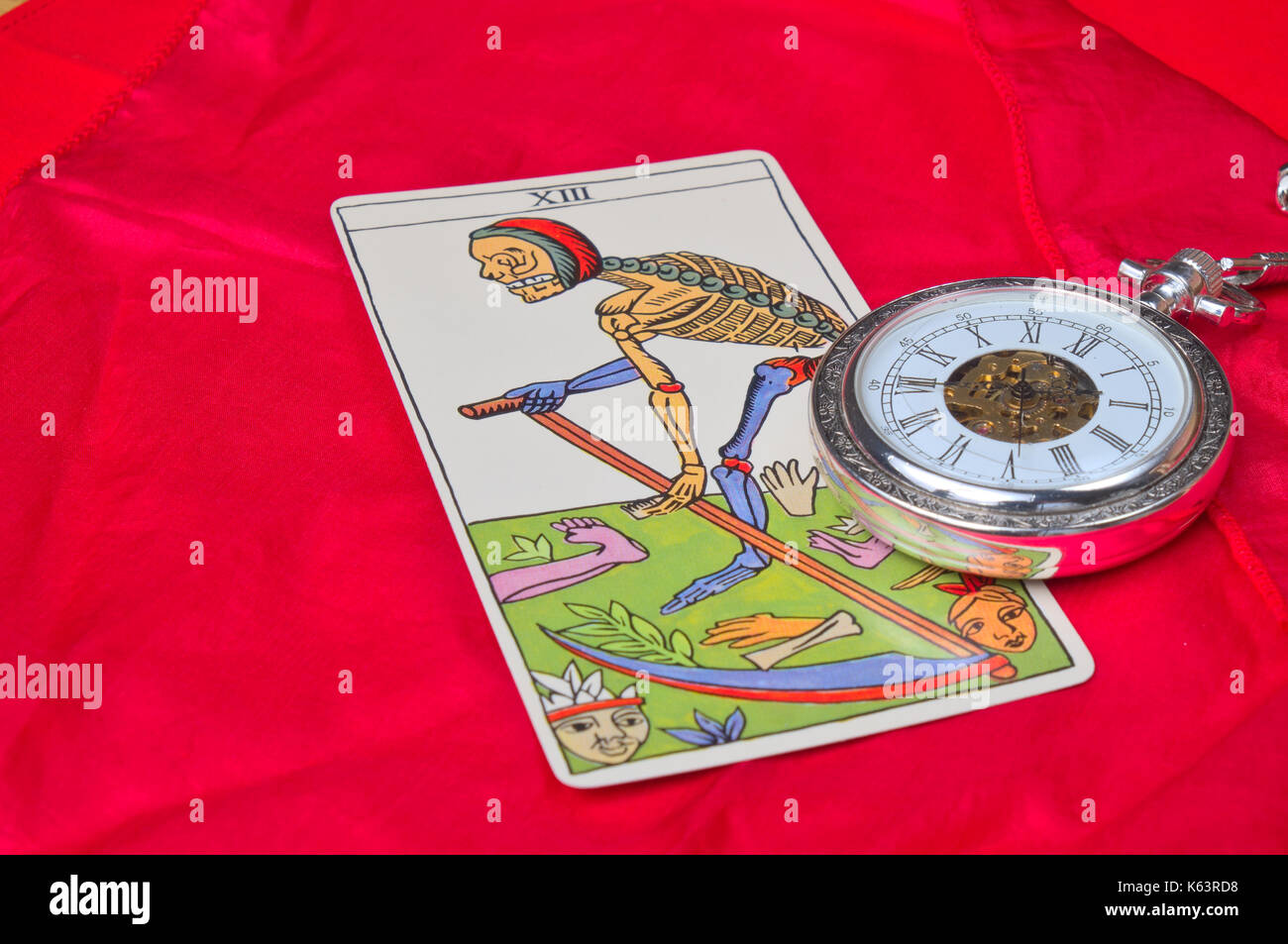 Pocket watch and death tarot card on a red silk cloth. Vintage and esoteric theme Stock Photo
