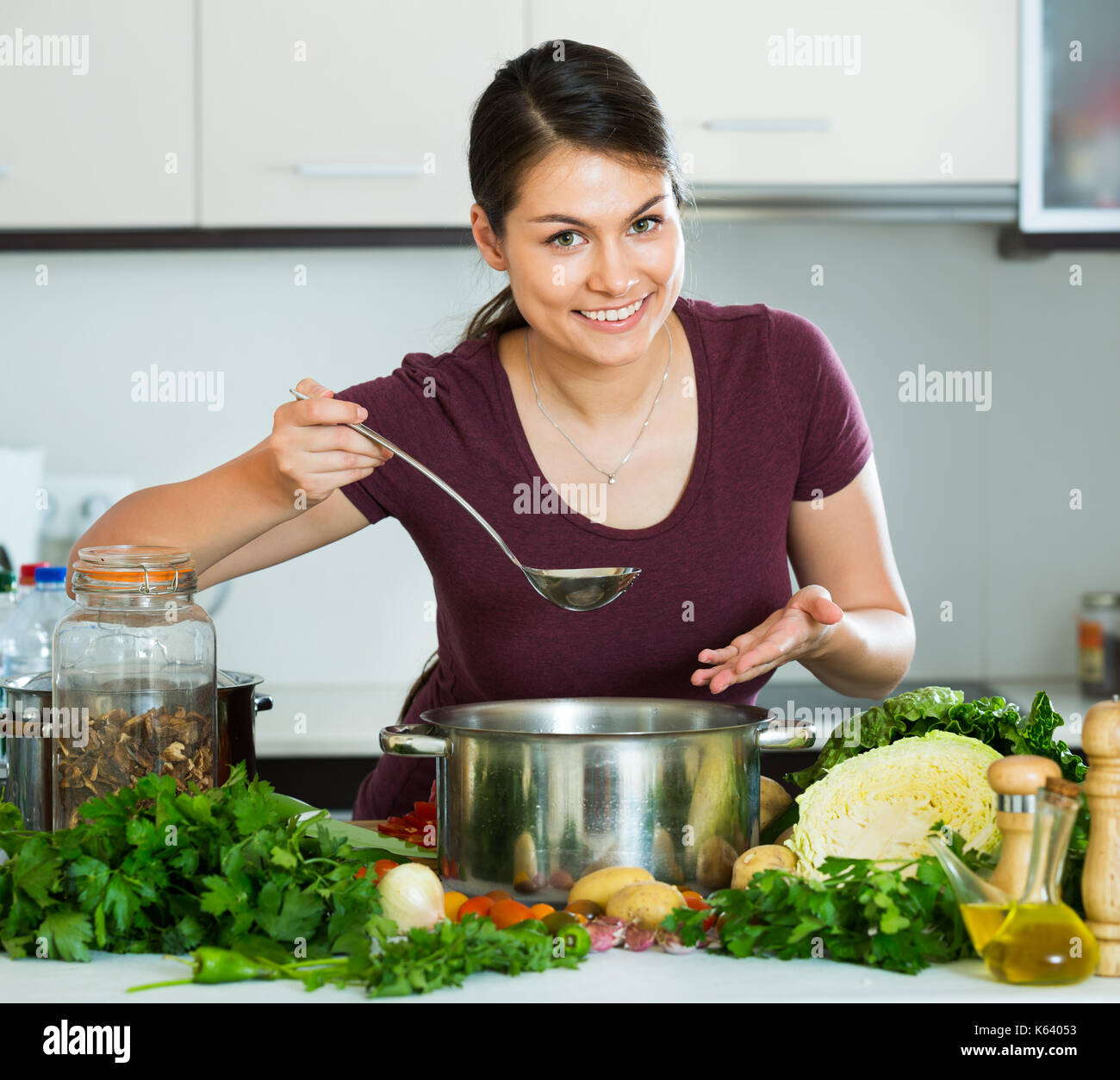 Pretty young brunette cooking the vegetables in a domestic kitchen ...