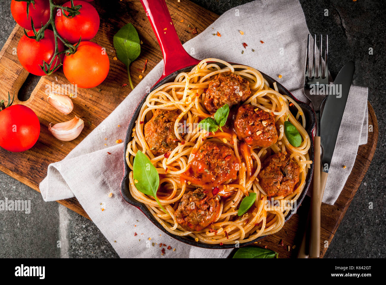 Spaghetti pasta with meatballs, basil tomato sauce in red cast iron pan