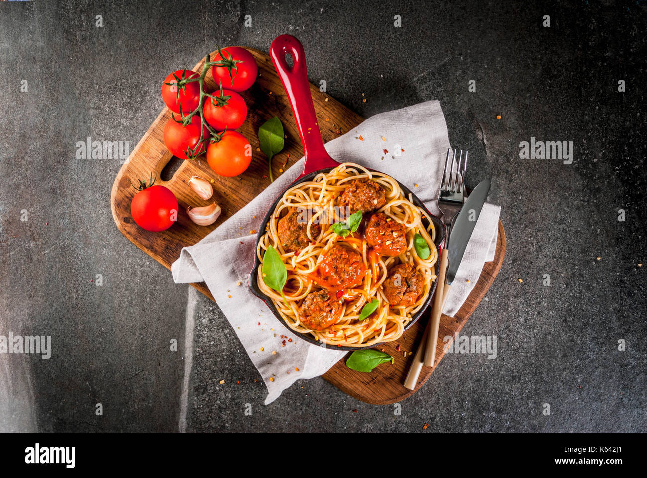 Spaghetti pasta with meatballs, basil tomato sauce in red cast iron pan