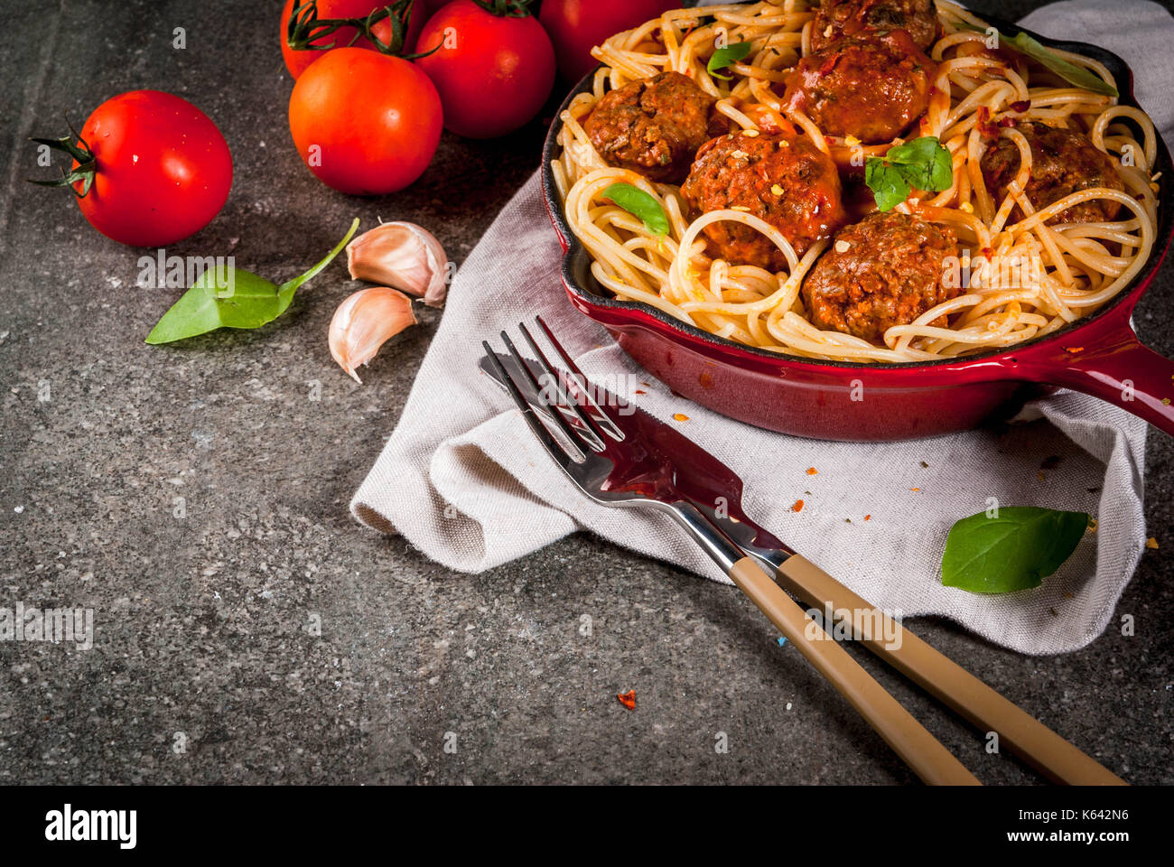 Spaghetti pasta with meatballs, basil tomato sauce in red cast iron pan