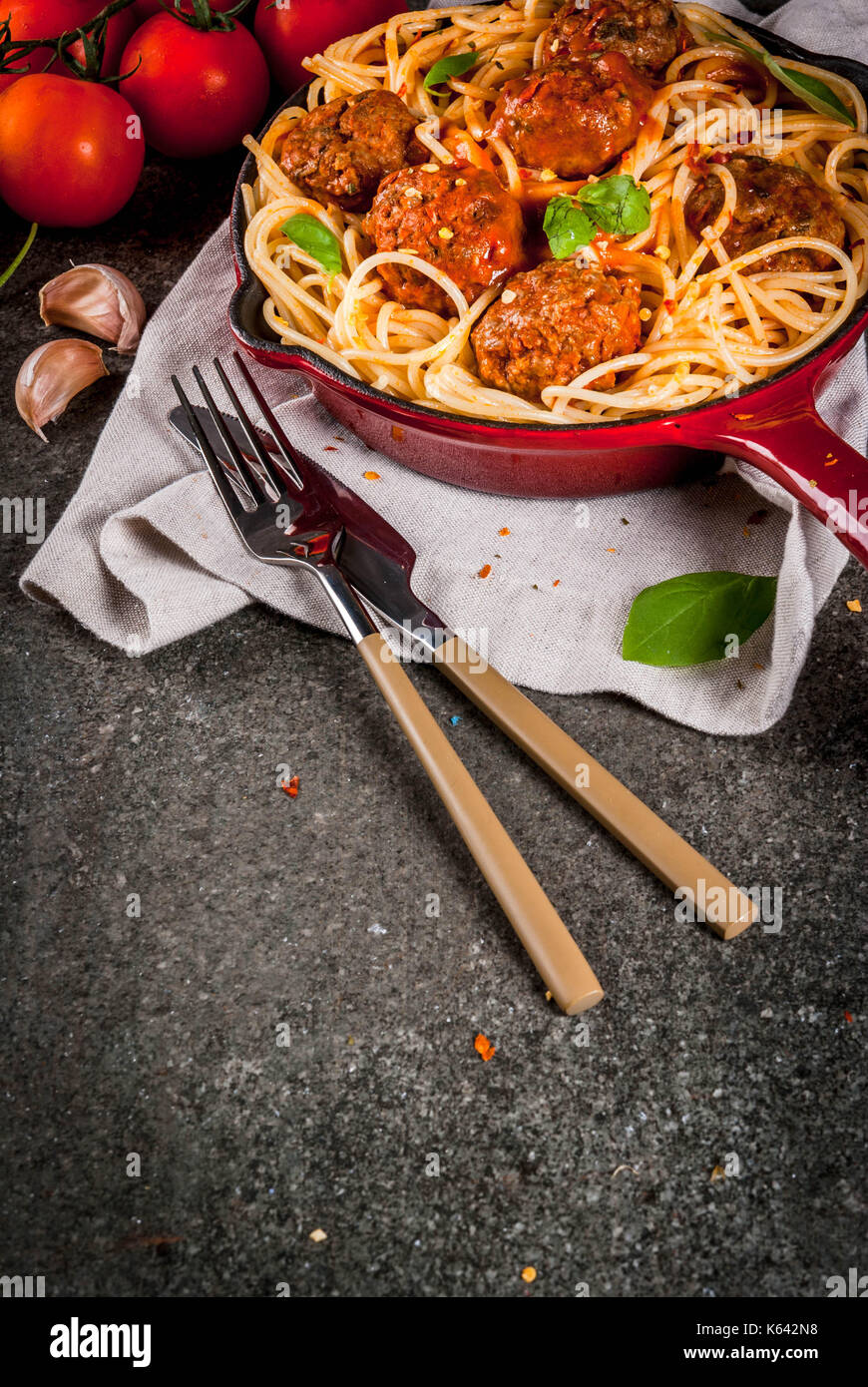 Spaghetti pasta with meatballs, basil tomato sauce in red cast iron pan