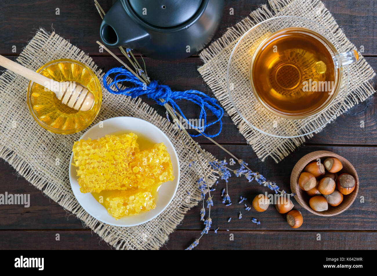 A cup of herbal tea, honey, honeycomb, hazelnuts on a dark wooden background. Healthy foods. Proper nutrition. Stock Photo