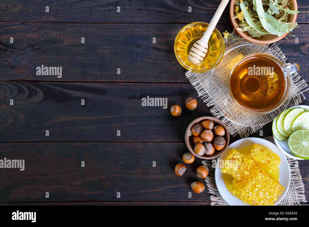 A cup of herbal tea, honey, honeycomb, hazelnuts on a dark wooden background. Healthy foods. Proper nutrition. Stock Photo