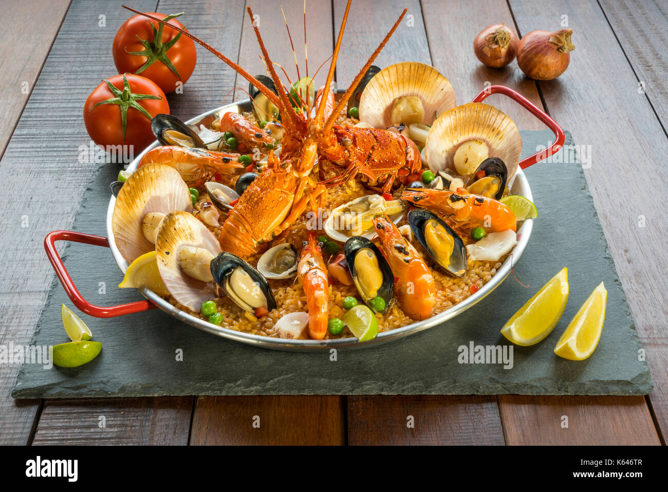 Gourmet seafood Valencia paella with fresh langoustine, clams, mussels and squid on savory saffron rice with prawn, scollops, mussels and lime slices, Stock Photo