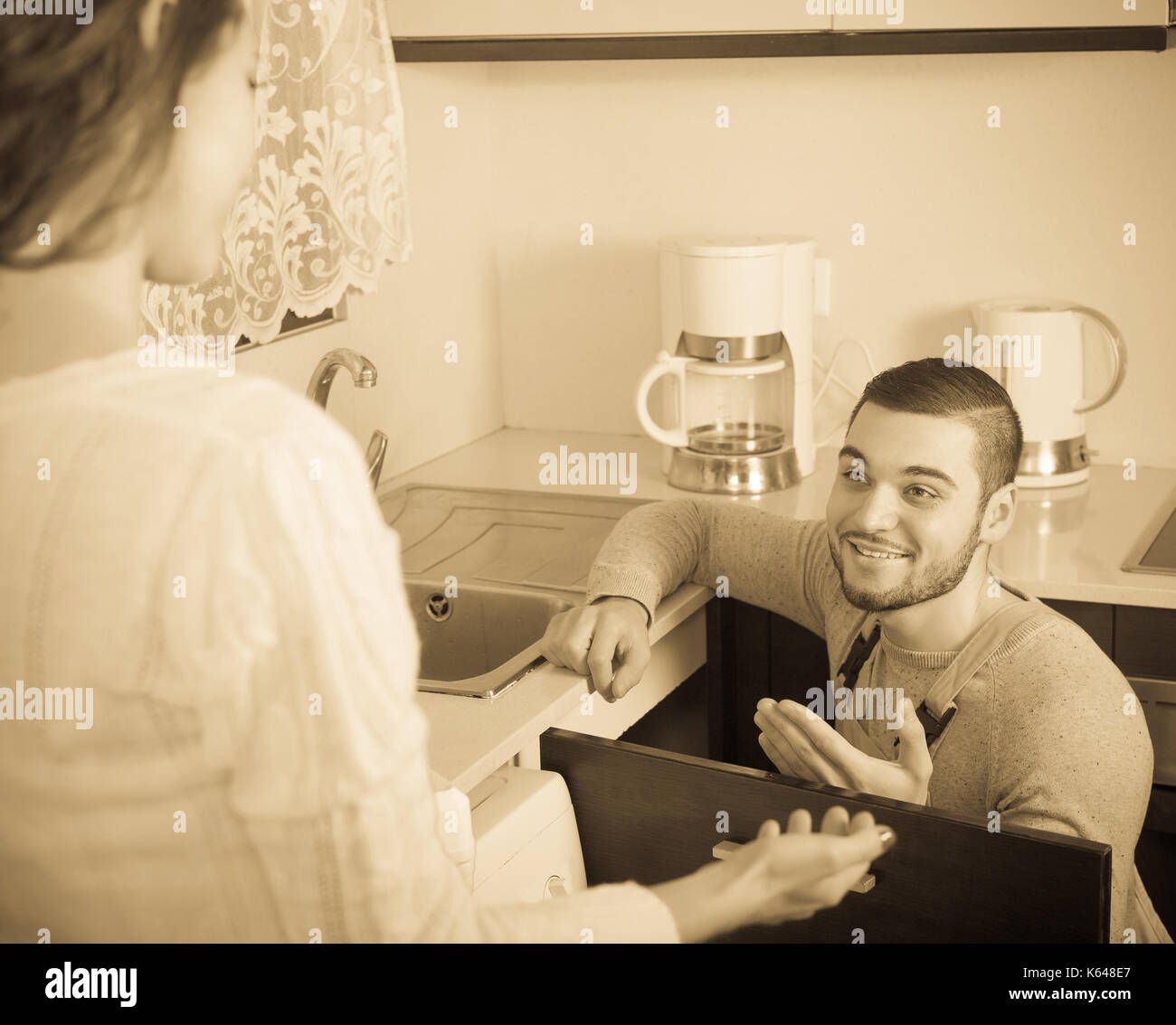 Repairman repairing a running water for housewife Stock Photo Alamy
