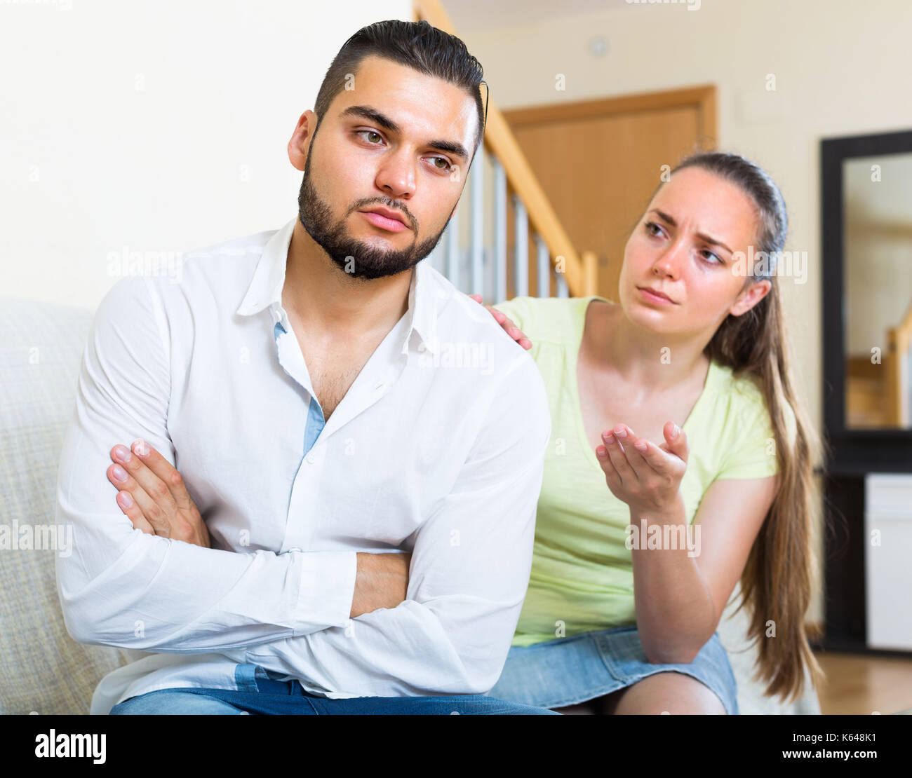 Depressed young couple sitting at the sofa and having quarrel. Focus on ...