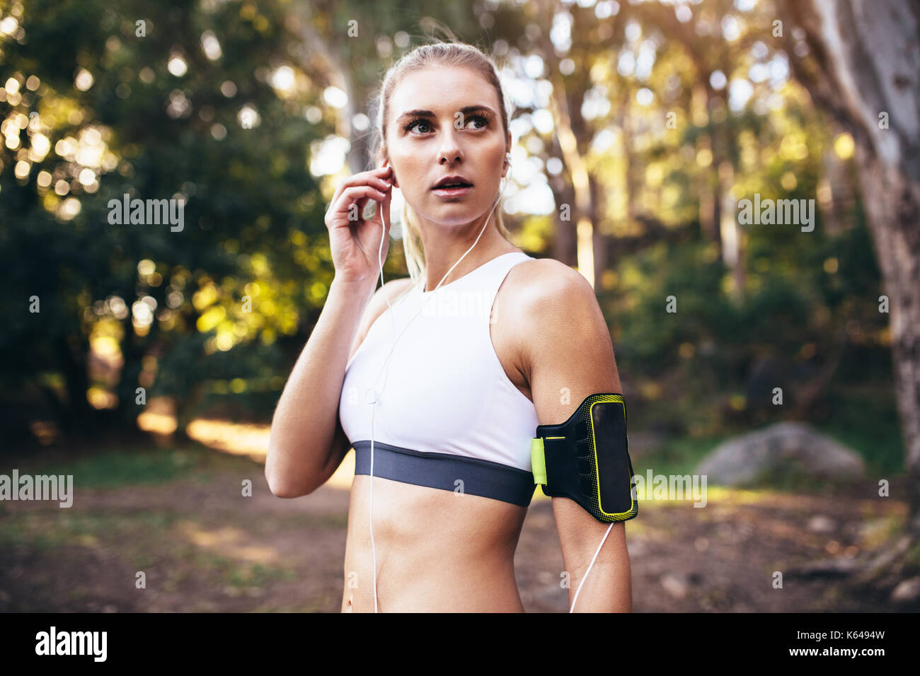 Woman wearing earphones looking away. Runner listening to music during morning jog. Stock Photo