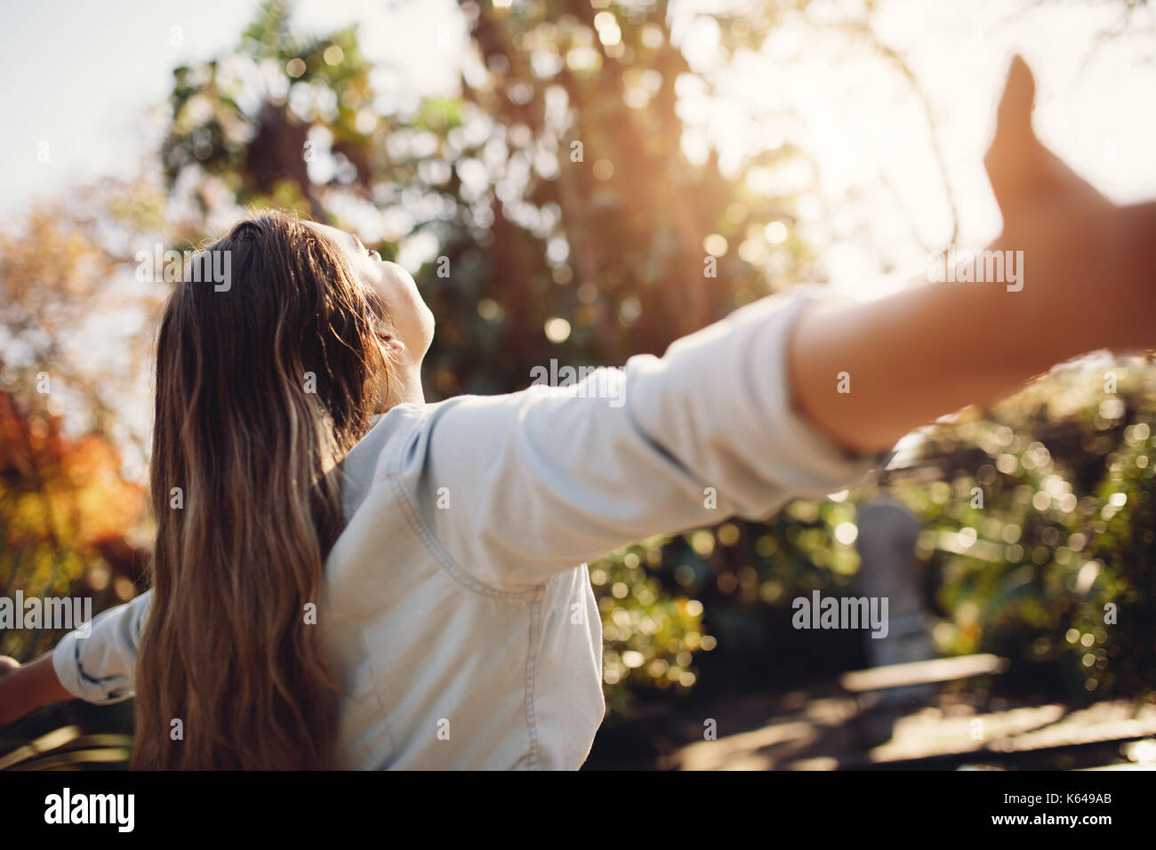Young woman spreading hands with joy and inspiration outdoors. Female feeling free with arms wide open. Stock Photo