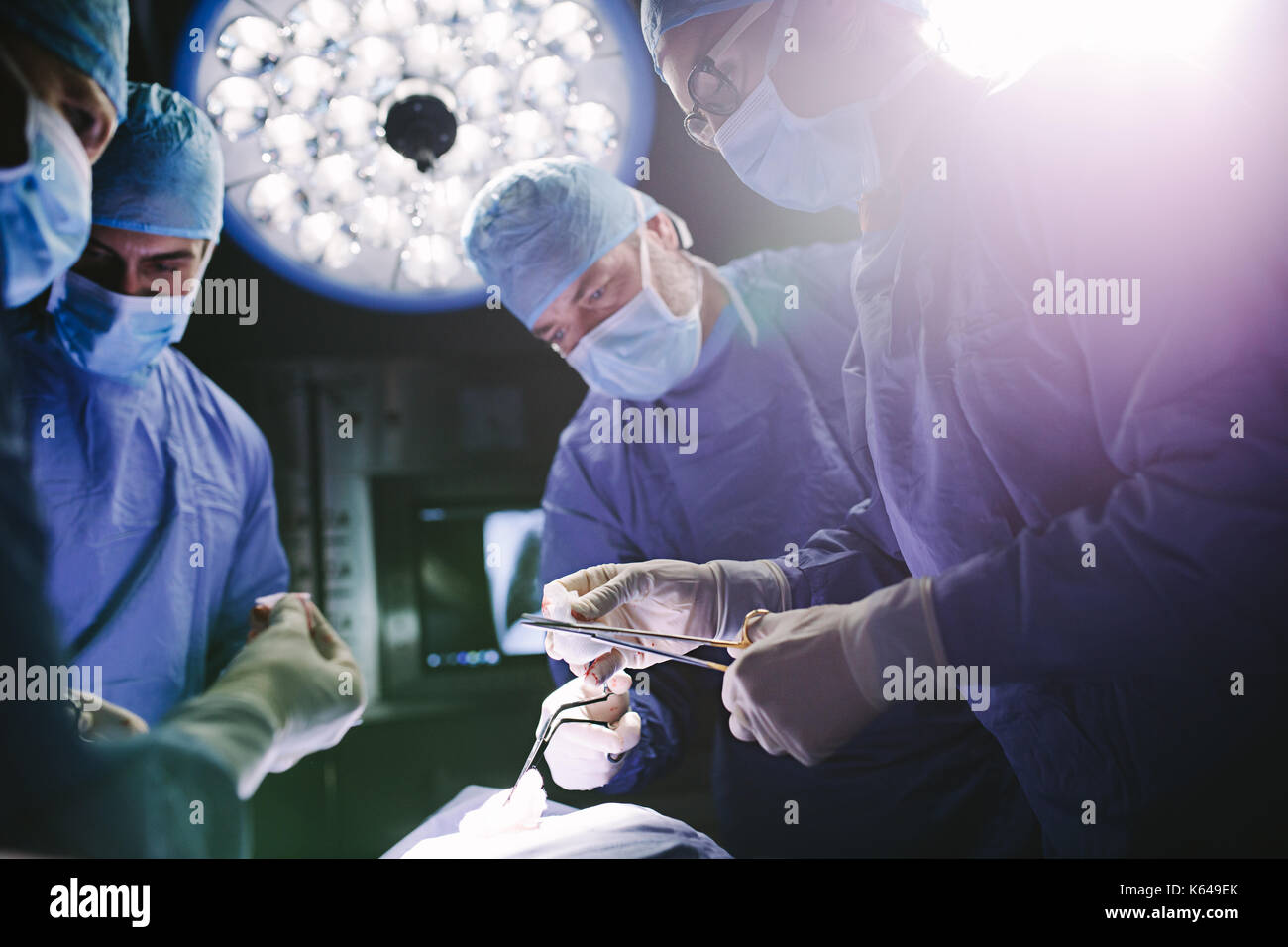Team of doctors performing surgical procedure in operating theater. Professional surgeons performing surgery in operating room of a hospital. Stock Photo
