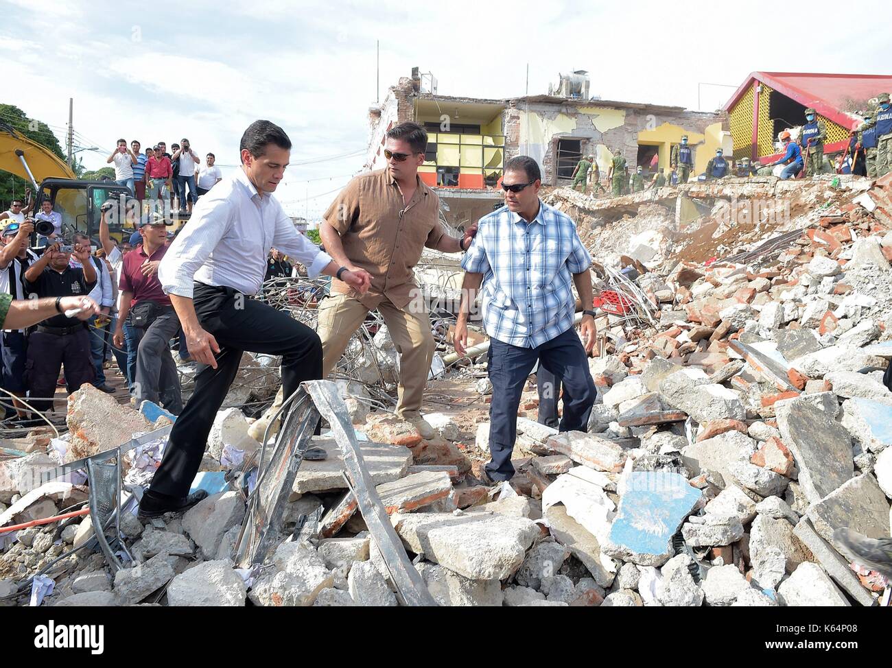 Mexican President Enrique Pena Nieto climbs over rubble to view a destroyed school caused by an earthquake during a visit to the coastal town closest to the epicenter September 9, 2017 in Juchitán, Oaxaca, Mexico. The massive 8.2-magnitude quake struck off the southern Pacific coast of Chiapas killing at least 60 people and leveling areas in some southern states. Stock Photo