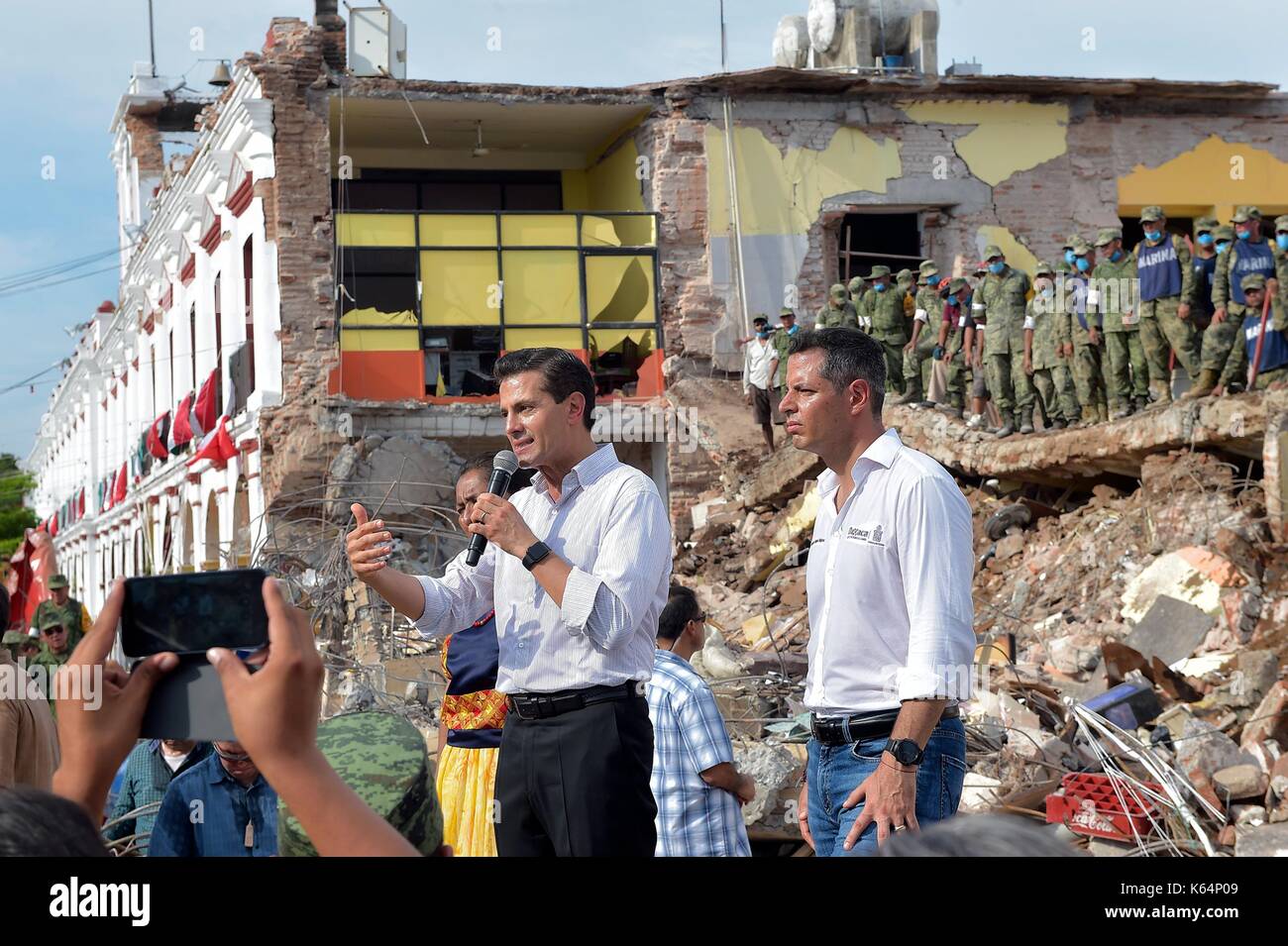 Mexican President Enrique Pena Nieto speaks to residents in front of a destroyed school as he views earthquake damage during a visit to the coastal town closest to the epicenter September 9, 2017 in Juchitán, Oaxaca, Mexico. The massive 8.2-magnitude quake struck off the southern Pacific coast of Chiapas killing at least 60 people and leveling areas in some southern states. Stock Photo