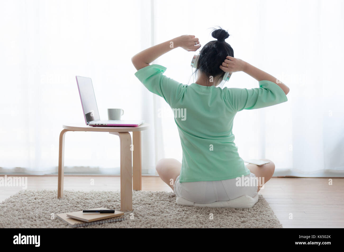 Young attractive Asian woman streching and exercise while working with laptop computer on sunday. Internet of things for modern lifestyle and freelanc Stock Photo