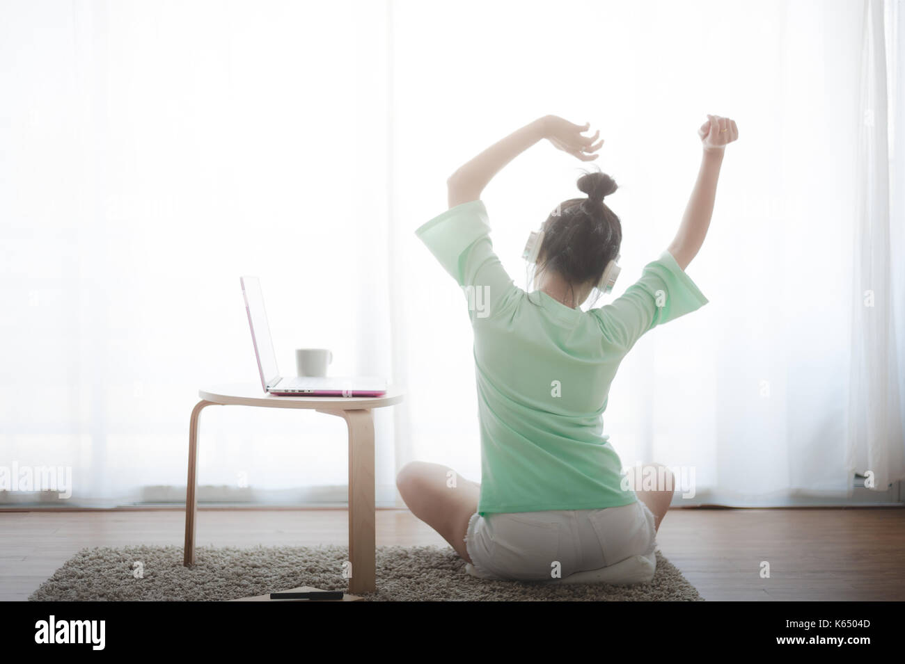 Young attractive Asian woman streching and exercise while enjoy listen to music on sunday. Internet of things for modern lifestyle and freelance worke Stock Photo