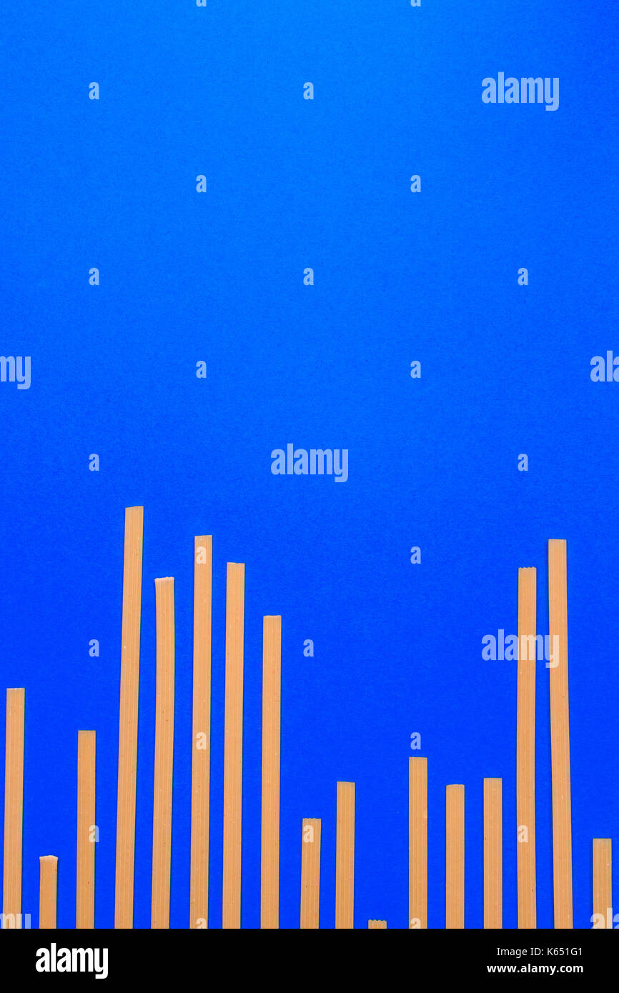 Blue background with yellow long raw pasta arranged in bar graph Stock ...
