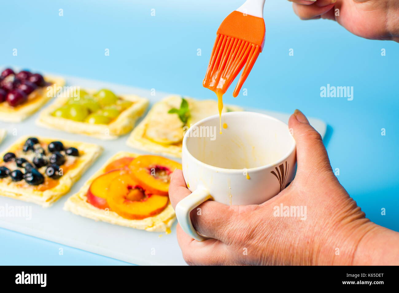 Chef applying egg on the fruit sweet pie before baking Stock Photo