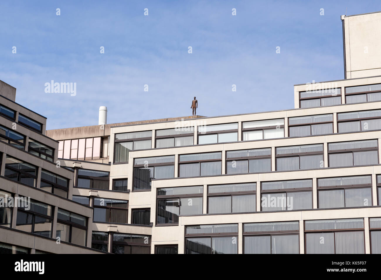 A life-sized cast iron sculpture by Antony Gormley on the roof of the library at the University of East Anglia, Norwich, UK. Stock Photo