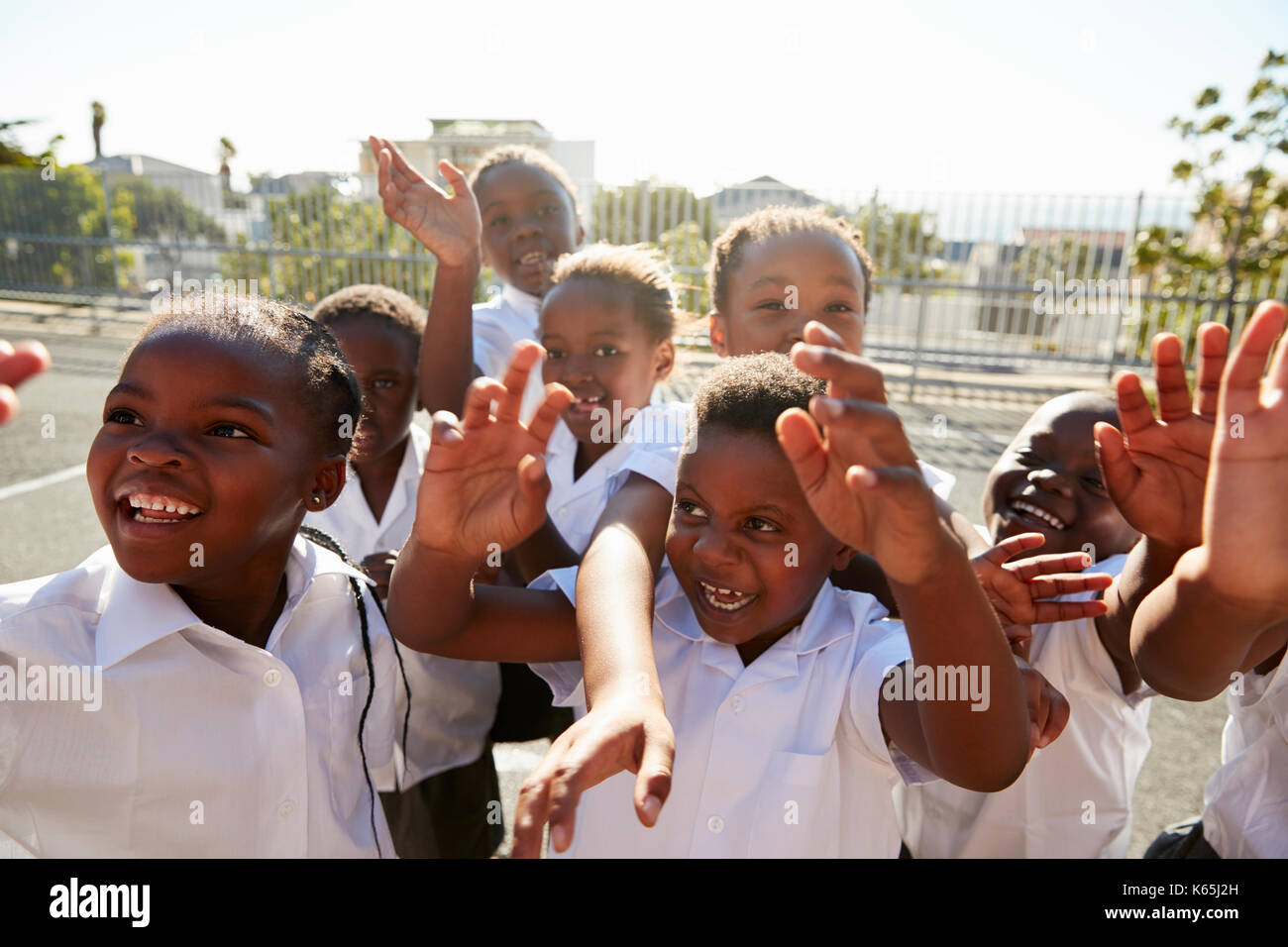Elementary school kids in playground waving to camera Stock Photo