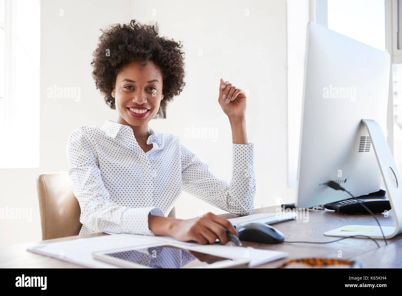 Young black woman in an office smiling to camera, close up Stock Photo ...