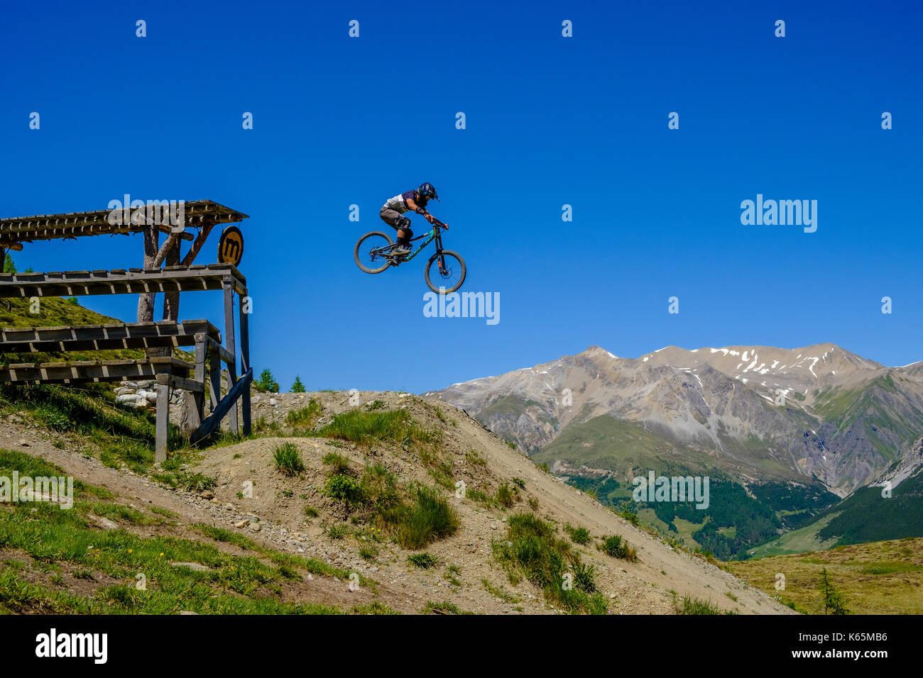 Downhill cyclist in action jumping down from a platform in the Motolino Bike Park Stock Photo