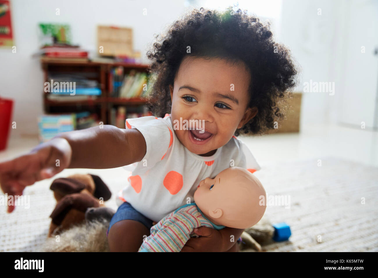 Happy Baby Girl Playing With Doll In Playroom Stock Photo - Alamy