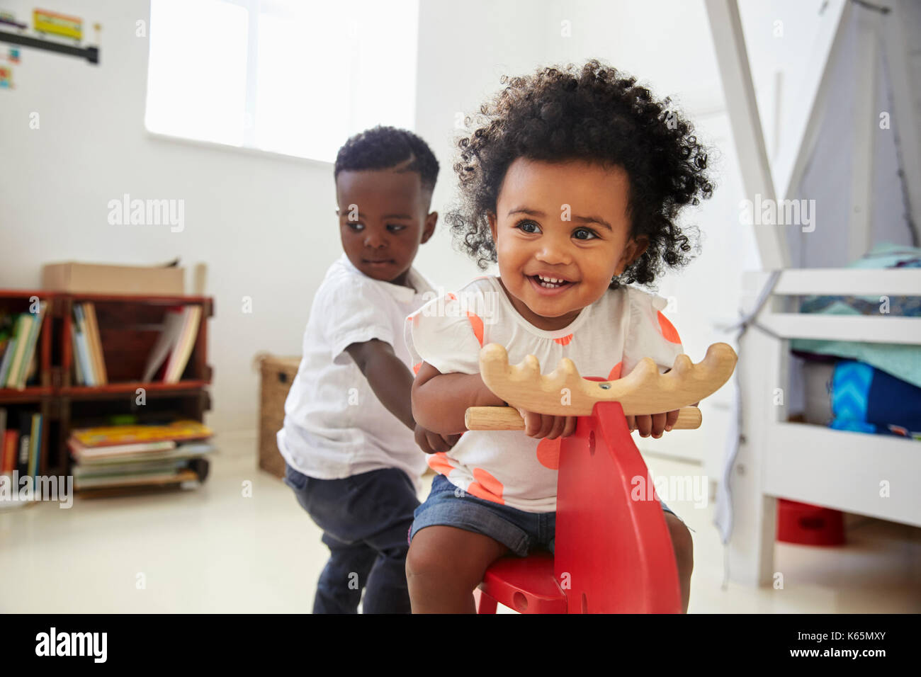 Two Children Sitting On Ride On Toy In Playroom Stock Photo - Alamy