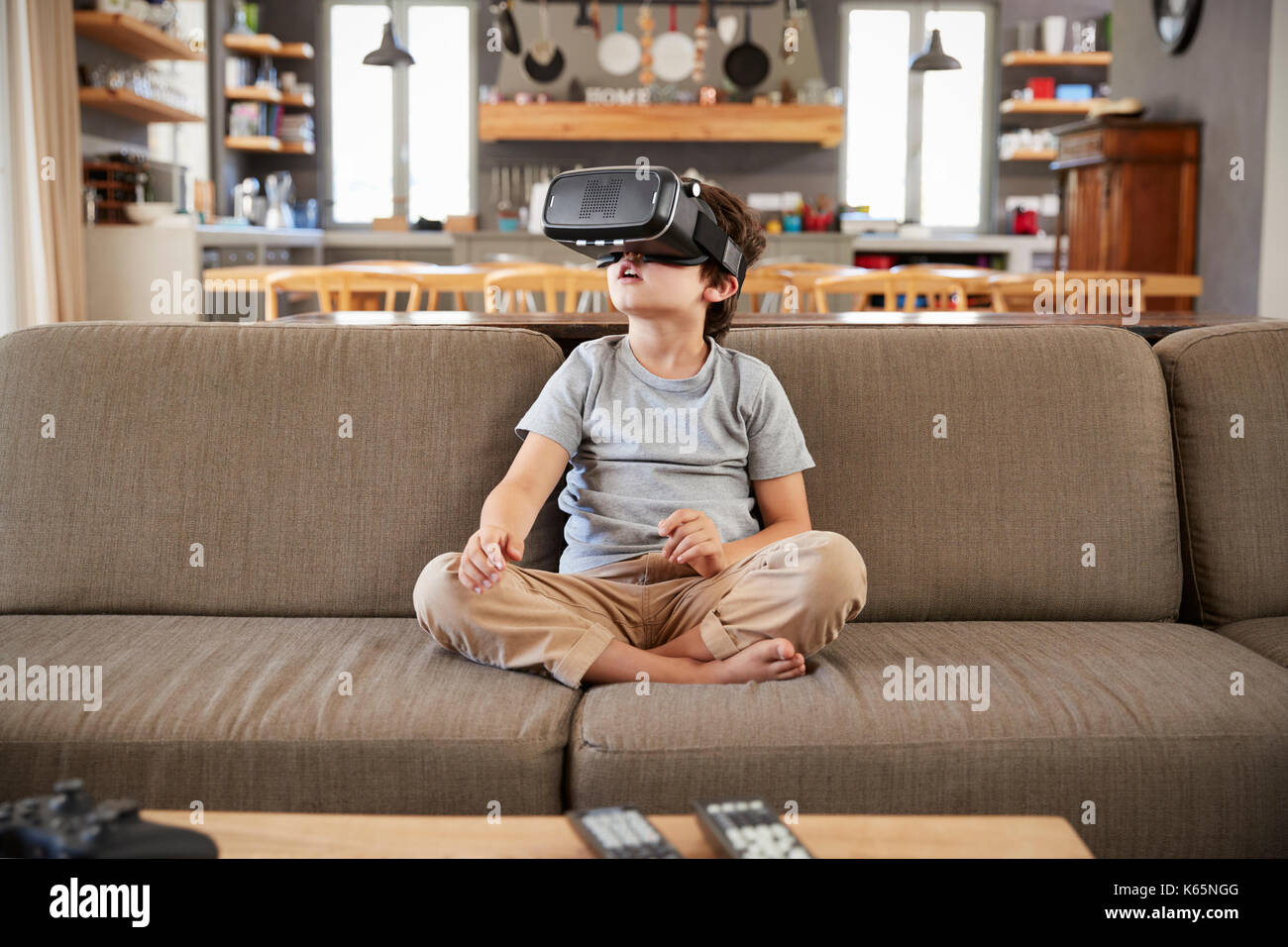 Boy Sitting On Sofa Wearing Virtual Reality Headset Stock Photo