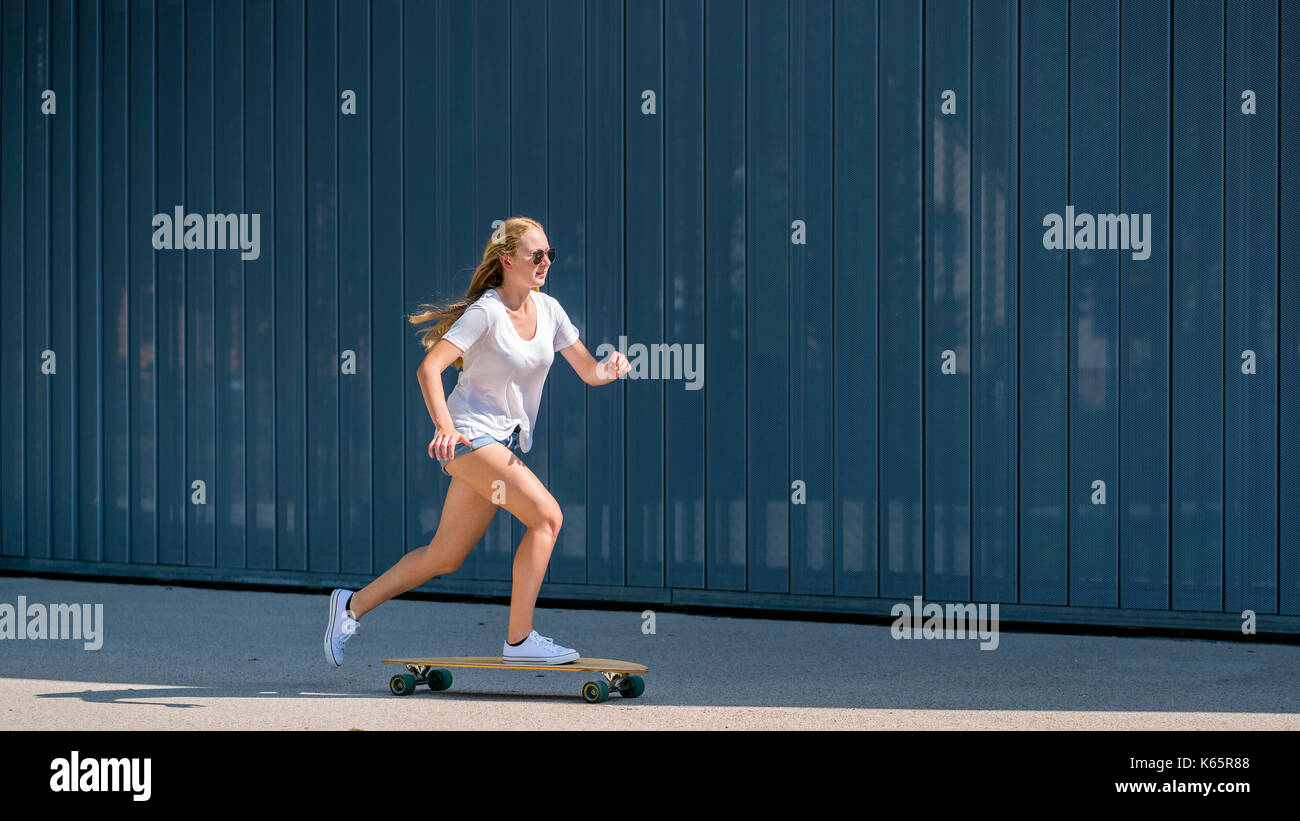 Woman, 22 years old, rides on longboard Stock Photo