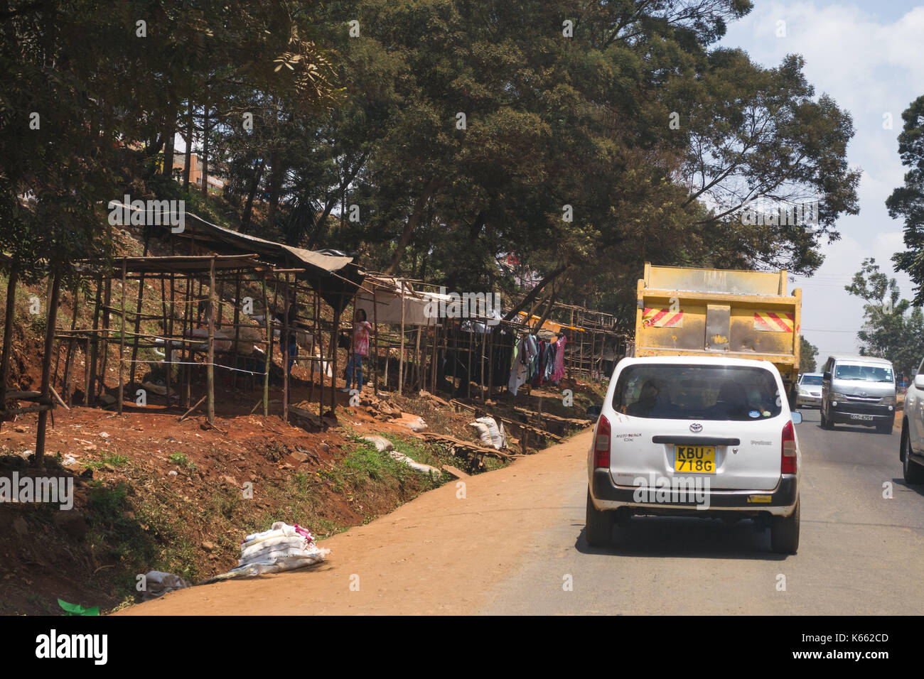 Wooden market stalls by roadside as vehicles drive past, Kenya Stock Photo
