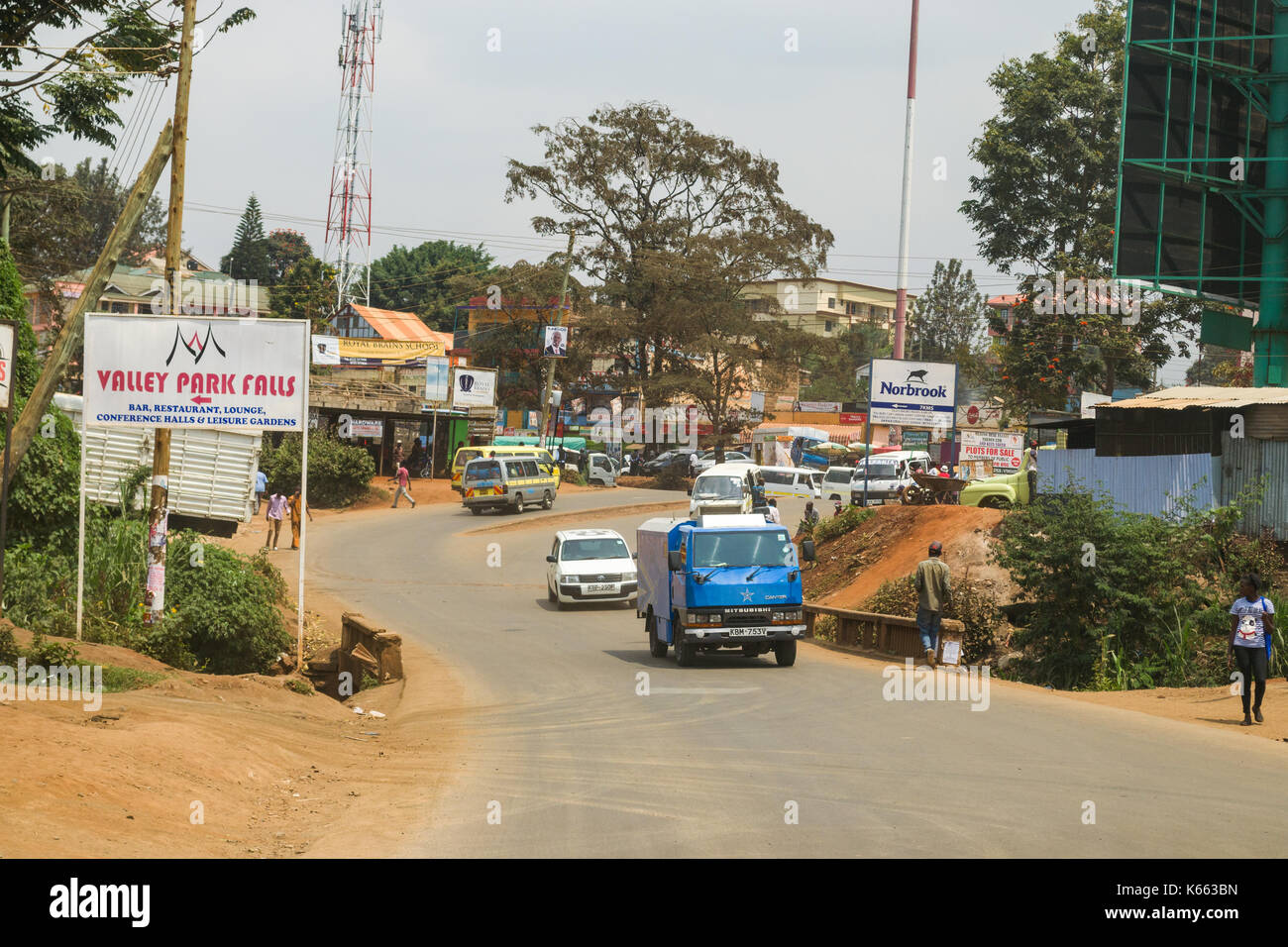 Vehicles on road through small town as people walk on roadside, Kenya Stock Photo