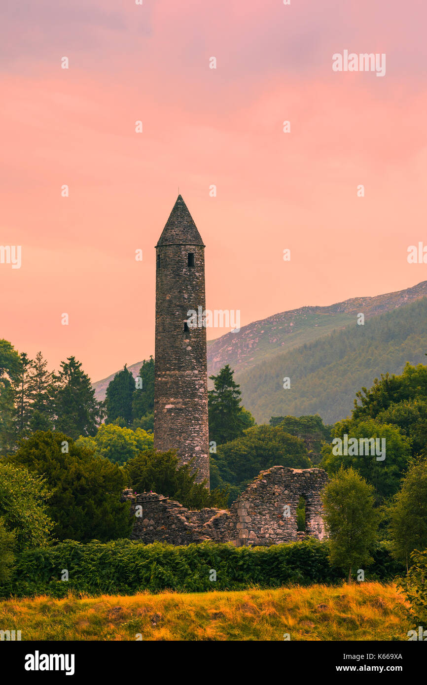 The round tower at Glendalough in County Wicklow, Ireland, renowned for an Early Medieval monastic settlement founded in the 6th century by St Kevin. Stock Photo