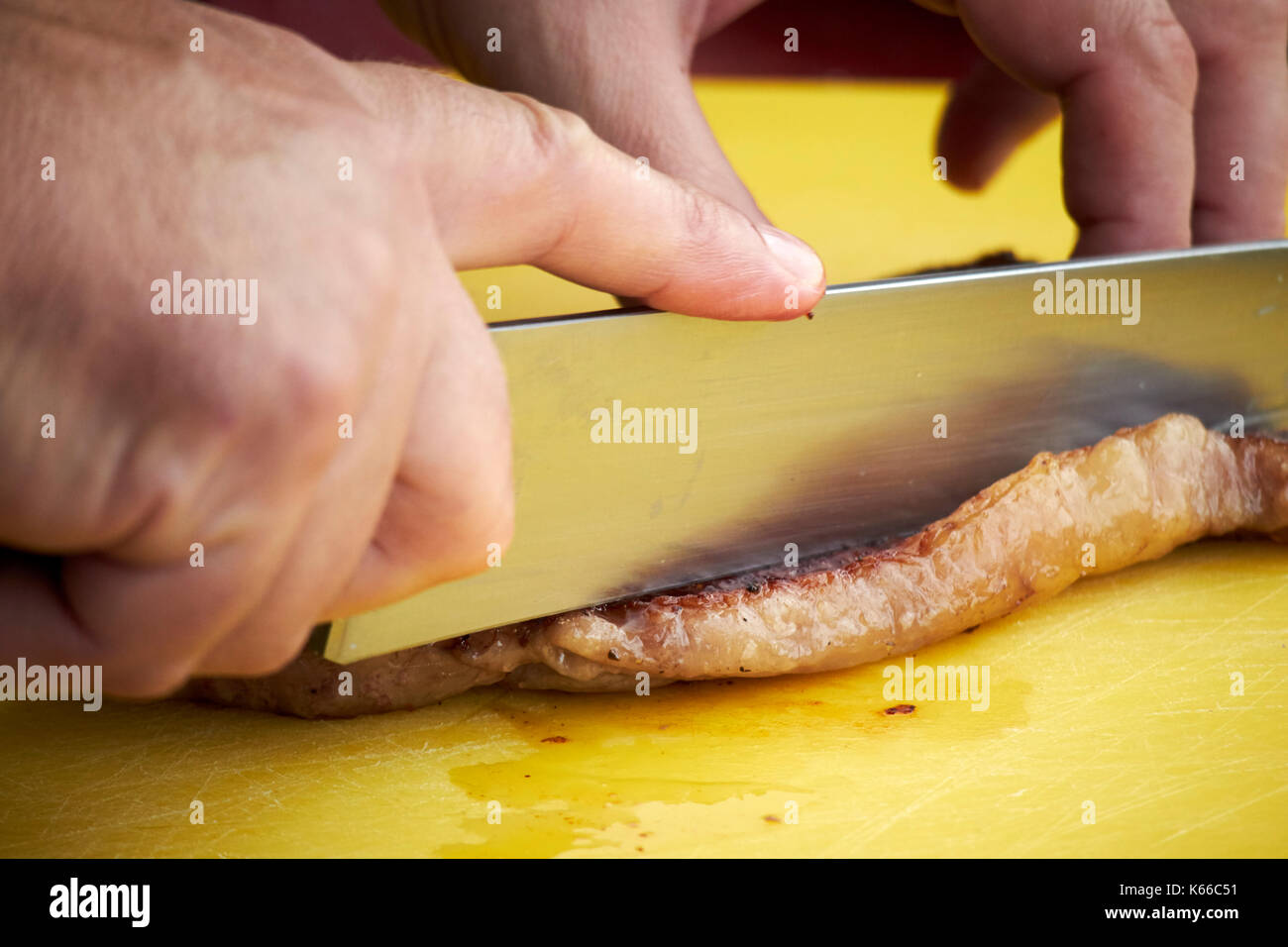 man cutting the fat off a piece of steak Stock Photo