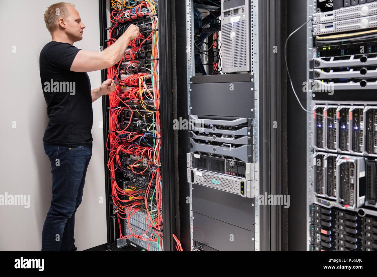 IT Technician Checking With Network Cables Connected To Servers Stock Photo