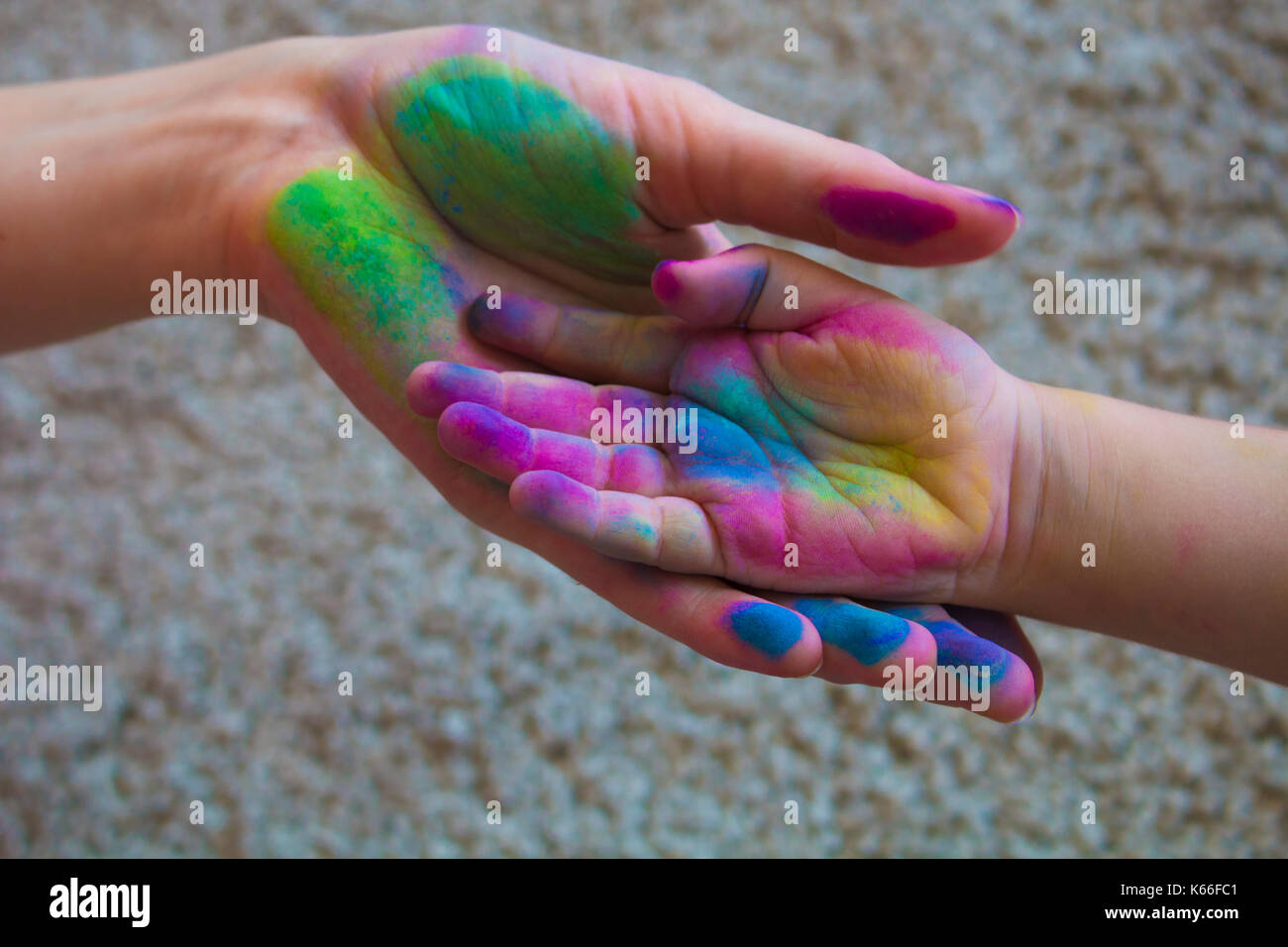 parental hand holds a palm of the baby painted with colored pastels Stock Photo
