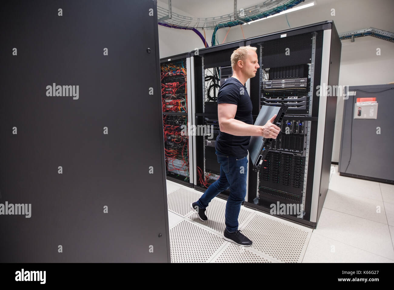 Male Technician Carrying Blade Server While Walking In Datacente Stock Photo