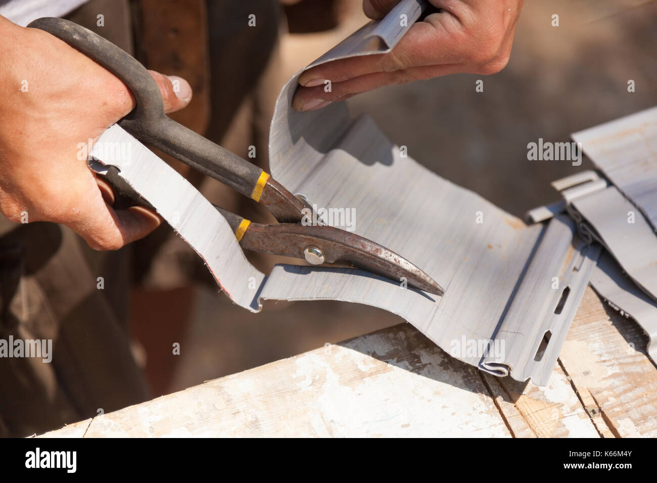 A construction worker cutting through vinyl siding using heavy duty shears in Ontario, Canada. Stock Photo