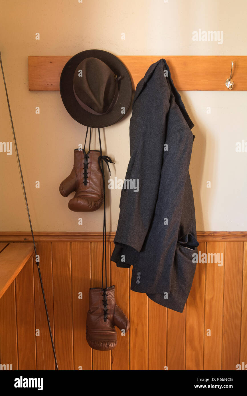 Vintage boxing gloves, hat, fishing rod, and wool coat hanging on coat hooks  with natural light Stock Photo - Alamy