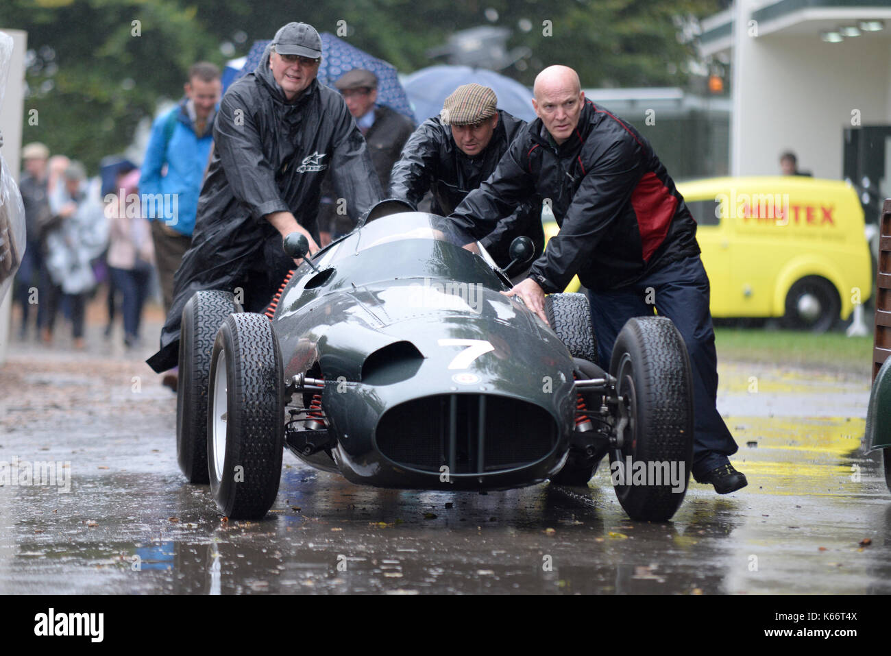 Vintage Grand Prix F1 racing car being pushed in rain by pit crew at Goodwood Revival 2017. Raining Stock Photo