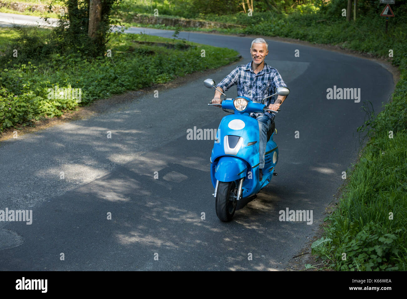 Caucasian man riding blue motor scooter Stock Photo