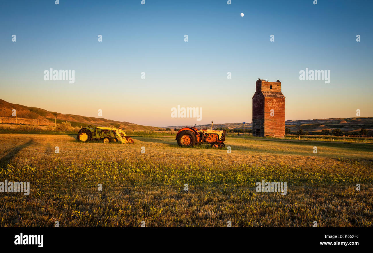 Tractors and abandoned grain elevator in the ghost town of Dorothy in Canada at sunset. Stock Photo