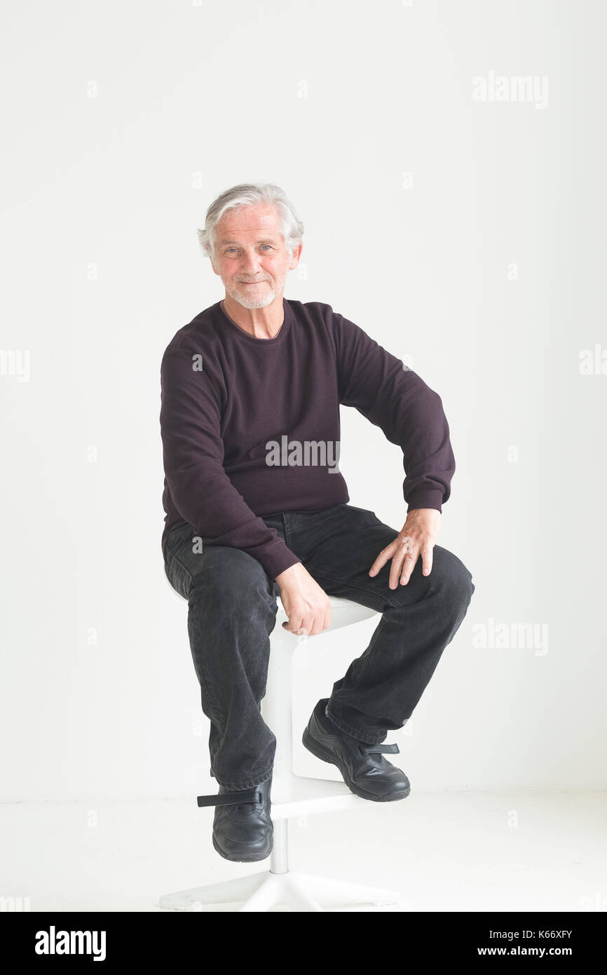 Older Caucasian man sitting on stool Stock Photo