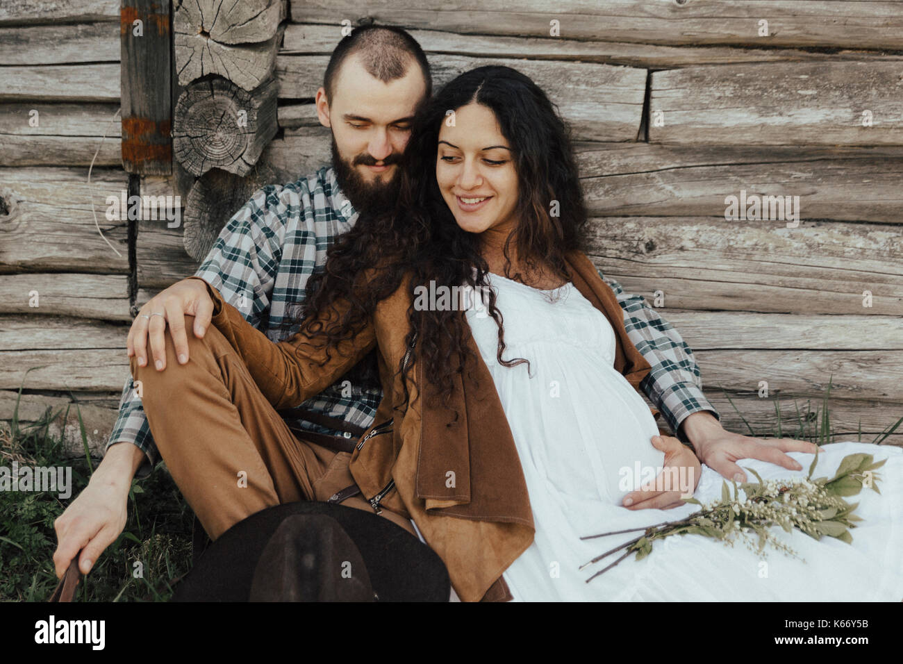 Caucasian cockle sitting in the grass leaning on wooden wall Stock Photo