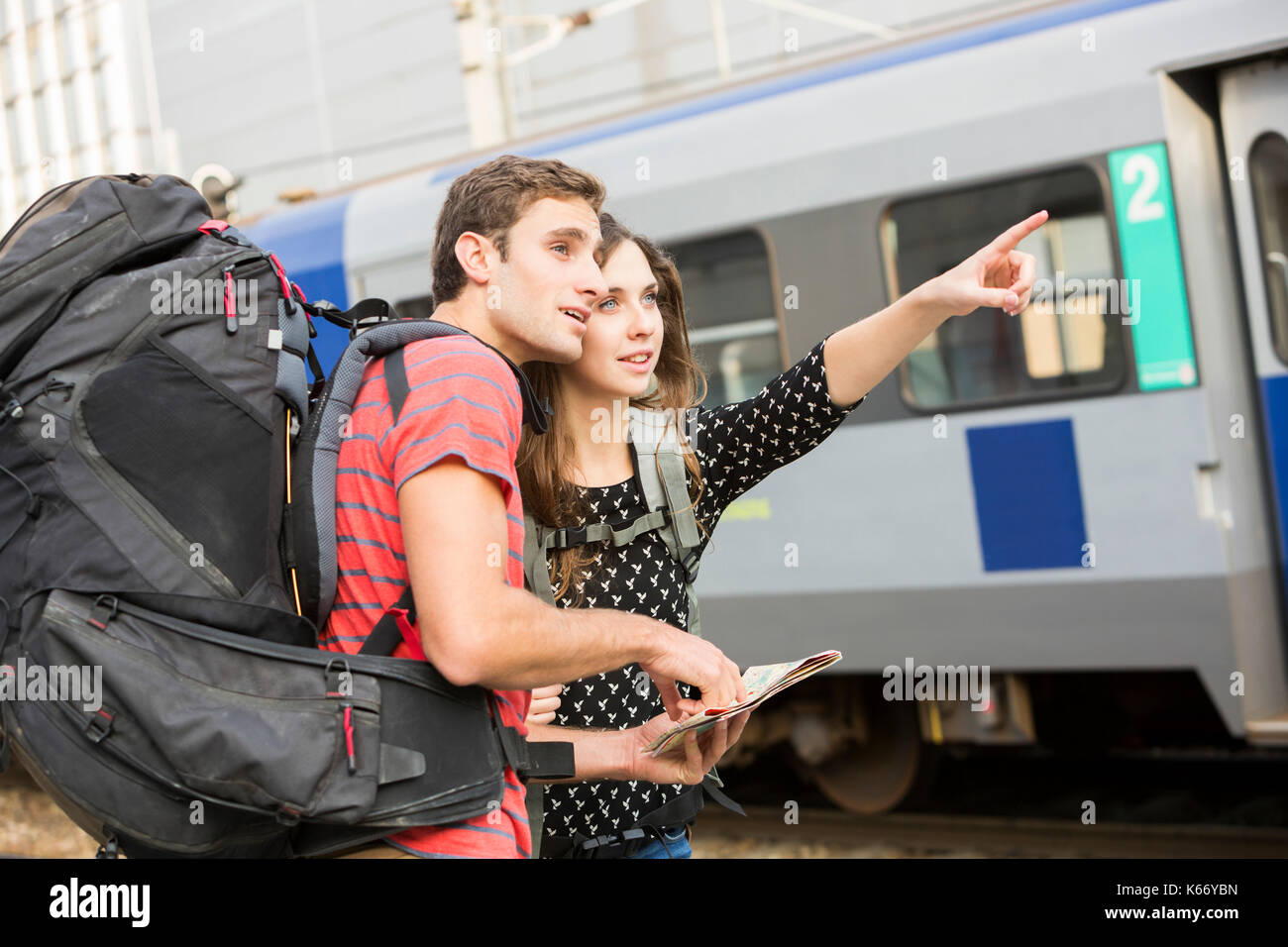 Caucasian couple reading map near train and pointing Stock Photo